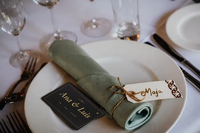 Mesa de boda con una NOIR card de Ana y Luis en el plato de cada invitado
